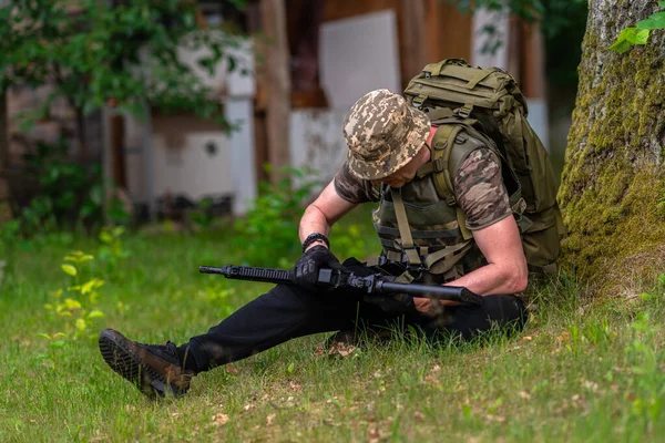 Uomo Camuffato Controlla Sua Arma Mentre Seduto Sotto Albero — Foto Stock