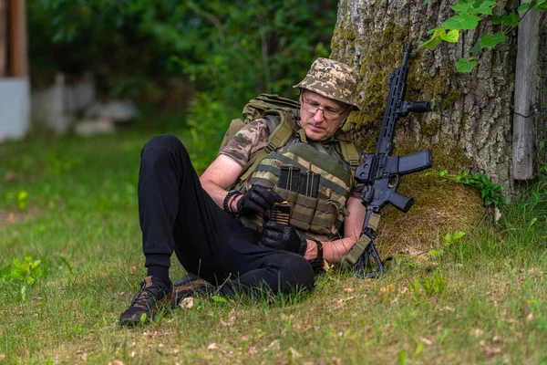 Soldato Mercenario Che Controlla Munizioni Mentre Seduto Sotto Albero Punto — Foto Stock