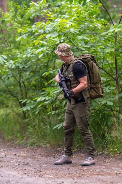 Tüfekli Bir Adam Yol Boyunca Bakar Yoğun Bitki Örtüsünün Arkasına — Stok fotoğraf