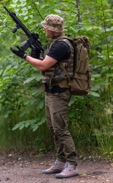男は森の中に立っている間に自動小銃を装填する — ストック写真