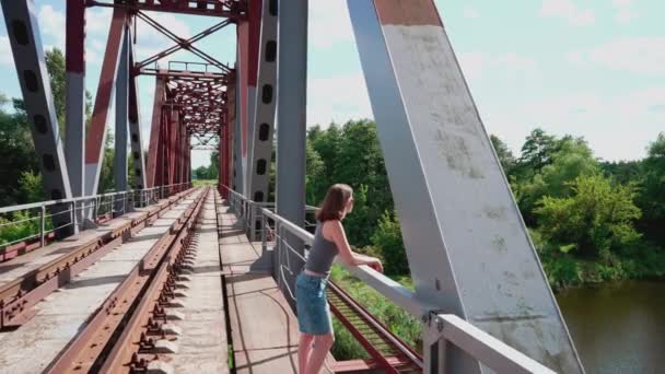 Das Mädchen Steht Auf Der Eisenbahnbrücke Und Lehnt Sich Ans — Stockvideo