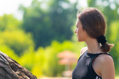Spor tişörtlü bir kızın kameradan yarım dönük görüntüsü.