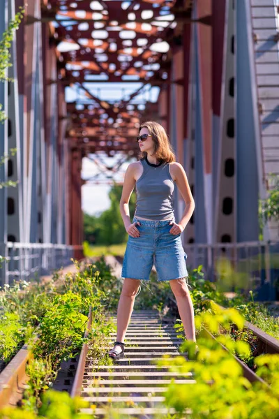 Дівчина Стоїть Залізничному Мосту Посеред Рейок Впевнено Склавши Руки Петлях Ліцензійні Стокові Фото