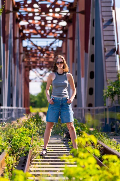 Молодая Женщина Смотрит Камеру Уверенно Стоя Посреди Железнодорожного Моста Стоковое Фото