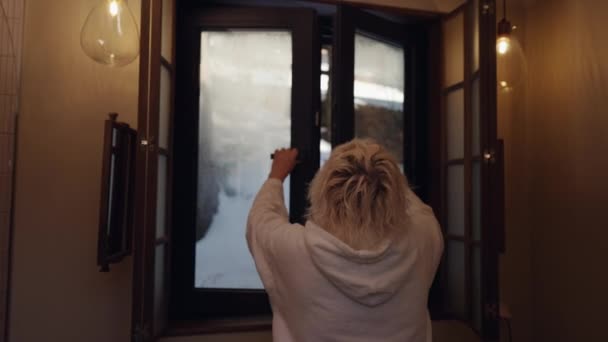 一个穿着毛茸茸的长袍的女人关上浴室的雾蒙蒙的窗户 — 图库视频影像