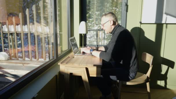 Hombre Mediana Edad Utiliza Portátil Una Mesa Una Habitación Iluminada — Vídeos de Stock