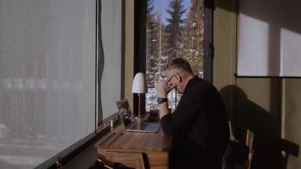 Hombre Pensativo Escritorio Usando Portátil Frente Las Ventanas Brillantemente Iluminado — Vídeos de Stock