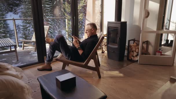 Ein Erwachsener Mann Sitzt Auf Einem Stuhl Wohnzimmer Vor Panoramafenstern — Stockvideo