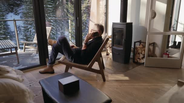 Homem Meia Idade Fala Telefone Enquanto Senta Uma Cadeira Sala — Vídeo de Stock