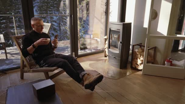 Mężczyzna Ogląda Wiadomości Przez Telefon Pijąc Herbatę Siedząc Salonie Przed — Wideo stockowe