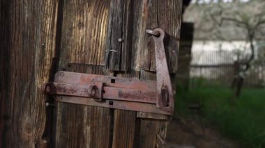 Harap olmuş ahşap bir kapıdan sarkan paslı bir menteşe..