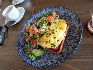 Arugula ve somon salatalı kızarmış ekmek üzerine Benedict usulü yumurta.