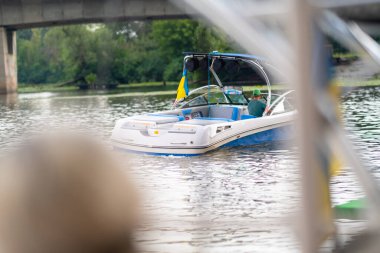 Bir adam köprünün altından geçmek için bir tekneyi nehirden aşağı sürüyor..