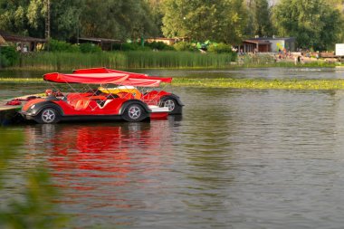 Katamaranlar, kıyıya yakın park etmiş nehir eğlencesi için araba olarak stilize edildiler..