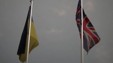 Ukrayna ve Büyük Britanya 'nın ulusal bayrakları bayrak direkleri üzerinde birlikte dalgalanır..