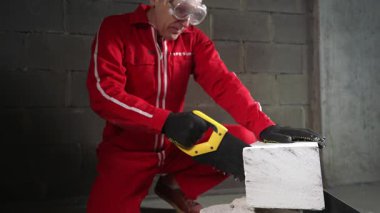 Bir işçi, karpit dişli testereyle beton bloğu parçalara ayırıyor..