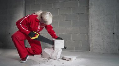 Kadının biri beton bir bloğu testereyle parçalara ayırıyor..