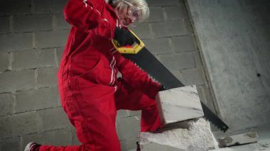 El testeresi ile blokları keserken uçan tuğla parçacıkları.