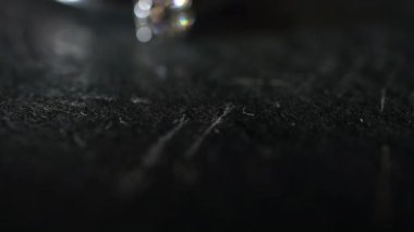 Karanlık bir taş yüzeyde duran bir elmas yüzüğe odaklan..