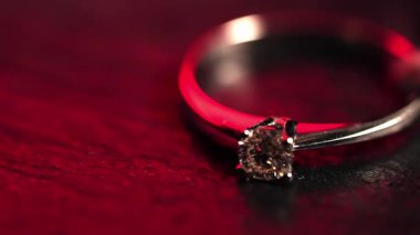 Kırmızı ışıkla aydınlatılan elmasla beyaz değerli metalden yapılmış bir yüzük..