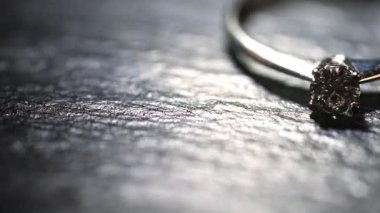 Koyu taş bir dokunun üzerinde duran elmas yüzüğün değişken aydınlanması..