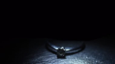 Elmas yüzüğün bir kısmı bir ışık noktasında koyu bir arkaplanda görünür..