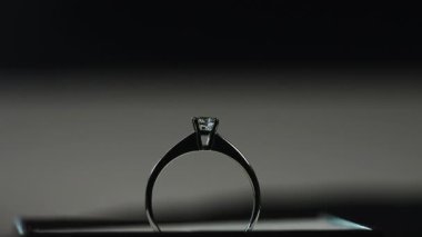 Beyaz değerli metalden yapılmış bir yüzükteki elmas üzerine düşen parlak ışık ışınlarından parlar..