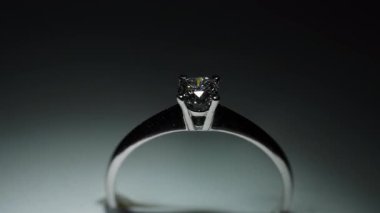 Beyaz altından ya da platinyumdan yapılmış bir elmas yüzüğün parıltısı ışığın etkisi altında.