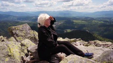 Dağın zirvesine ulaşmış bir yürüyüşçü, açılan manzaraya bakar..