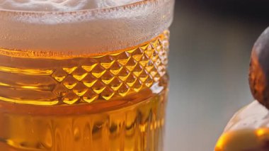 Bir bardak kehribar birası ve dana pirzola, peynir ve patates kızartması tabağında baharat ile sulu bir burger..