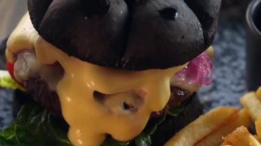 Köfteli, peynirli, turşulu, otlu, domatesli ve patates kızartmalı bir hamburger..