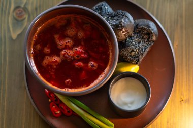 Ukrayna kırmızı borsası siyah çörekler, yeşil soğanlar ve ekşi kremayla servis edilir. Üst görünüm.