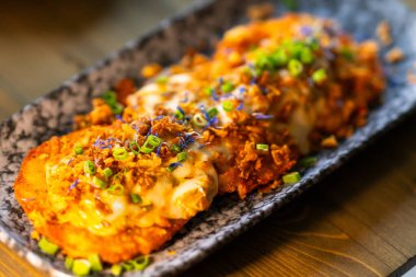 Tabakta yeşil soğan ve peynir serpiştirilmiş patates krepleri var..