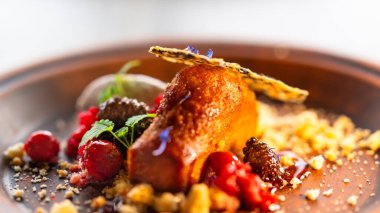 Ahududu, çilek, bal, çırpılmış krema ve nane yapraklı bal süngeri keki servis edilir..