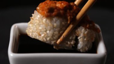 İçinde karides, yılan balığı ve baharatlı domates bulunan bir suşi rulosu soya sosuna batırılır..