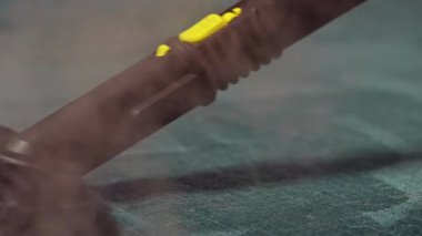 Buhar jeneratörü fırçasıyla döşeme kumaşını temizleme sürecinin ayrıntılı bir görüntüsü.