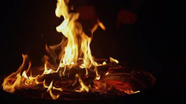 Bir adam ateş çukurunda yanan ateşin altına koyarak ellerini ısıtır..