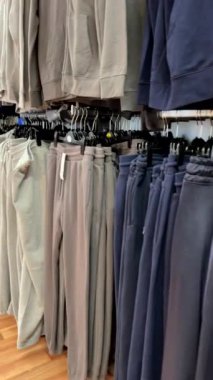 Mağaza demiryollarında asılı erkek eşofmanları ve koşucuları gösteren dikey video.