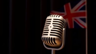 Union Jack, Büyük Britanya bayrağı karanlık sahne perdesinin önünde klasik tarzda mikrofon sallıyor..