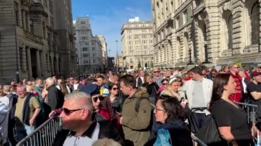 Farklı ülkelerden gelen halk, turistler, Eurovision Şarkı Yarışması hayranları güzel güneşli bir günde Liverpool şehrinin sokaklarındaki Eurovision Village girişinin güvenlik kontrolünde kuyruğa giriyorlar..