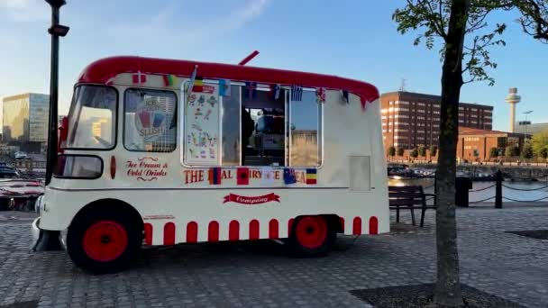 カラフルな古典的なヴィンテージのアイスクリームバンやアイスクリームトラックは 顧客を待っているリバプールのイングランド北西部のドックサイドに国旗の様々な装飾 — ストック動画