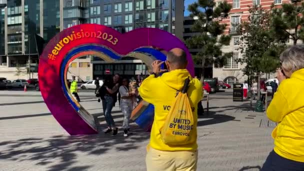 Voluntarios Eurovisión Toman Fotos Turistas Aficionados Posando Bajo Colorido Arco — Vídeo de stock