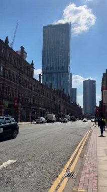 MANCHESTER, İngiltere, BİRLİK KINGDOM - 04.18.2023: Eski kırmızı tuğla ve modern cam ve metal mimarinin buluştuğu şehir merkezinde Deansgate yolunun dikey el kamerası görüntüsü.