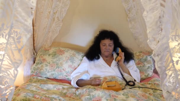 Kobieta Białym Szlafroku Pół Siedzi Półleżąc Łóżku Baldachimem Biorąc Telefon — Wideo stockowe