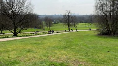  Uzak insanlar, çocuklu aileler, Manchester 'daki Heaton parkında bahar erken günlerinin tadını çıkarıyorlar, arka planda şehir merkezindeki gökdelenler..