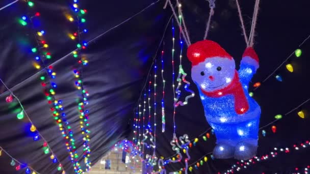 Kijkend Naar Kerstverlichting Tekenreeks Slingers Zwarte Achtergrond Verlicht Gloeiende Sneeuwpop — Stockvideo