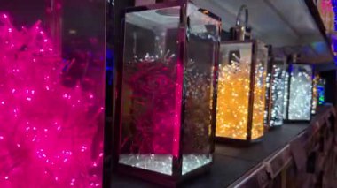 Rengarenk Noel ışıkları sıraları açık kutuların içine yerleştirilmiş çelenkler dükkan ya da mağaza raflarında yanıp sönüyor..