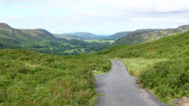Motosiklet sürücüsü ve yolcusu Eskdale 'den Hard Knott Geçidi' ne, Hardknott Geçidi 'ne kadar ingiliz Gölü' nün güzel bir dağ manzarasında yokuş yukarı gidiyorlar..