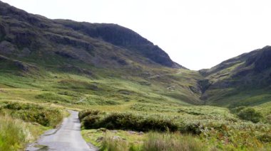 Motosiklet dağ geçidinin tepesine ulaşıyor, araba Hard Knott Pass Hardknott Geçidi 'nden İngiltere' nin Lake District bölgesindeki Eskdale 'e tek şeritli yoldan gidiyor..