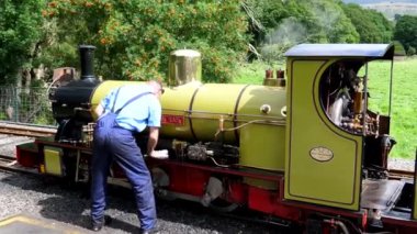Dar ölçü demiryolu hattının sonunda buharlı lokomotif veya motor temizleyen minyatür buhar treni sürücüsü, el kamerası görüntüsü. Dalegarth, Eskdale, Lake District, İngiltere.